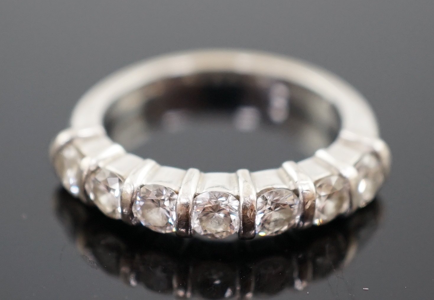 A modern 18ct white gold and seven stone round brilliant cut diamond set half hoop ring